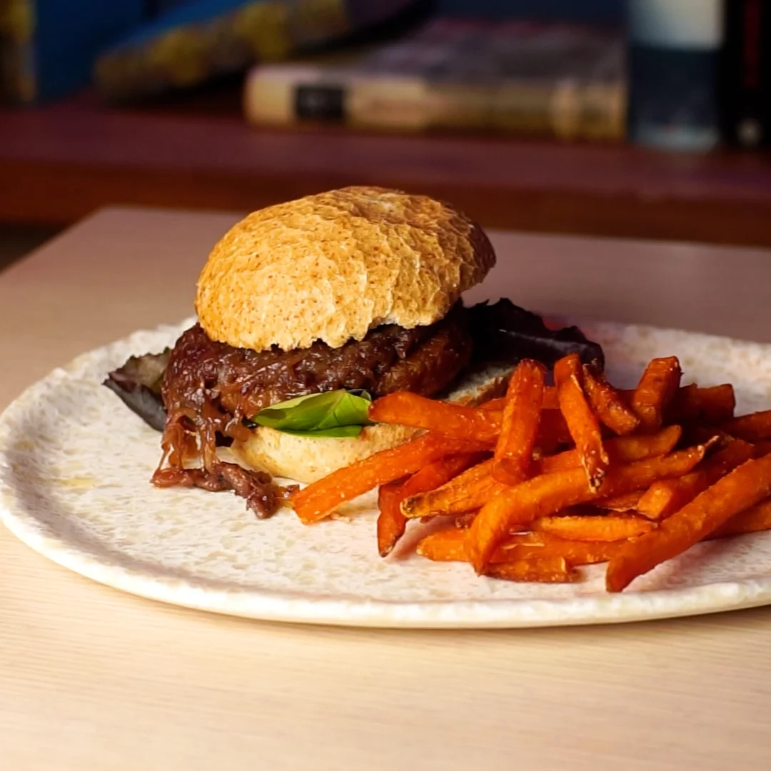 Vegan burger with mixed greens, caramelized onions and a round bun